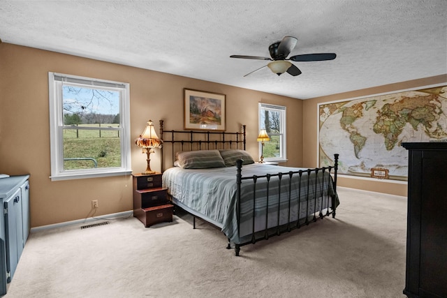 bedroom featuring ceiling fan, light colored carpet, and a textured ceiling