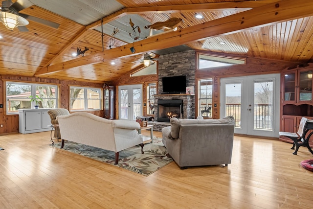 living room featuring a stone fireplace, light hardwood / wood-style flooring, wood ceiling, and french doors