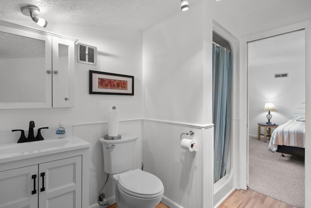 bathroom with toilet, a textured ceiling, vanity, a shower with shower curtain, and hardwood / wood-style flooring