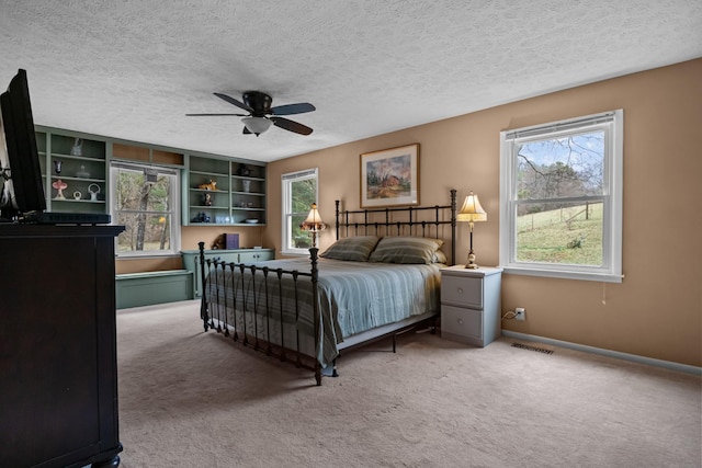 carpeted bedroom featuring ceiling fan and a textured ceiling