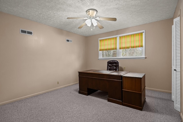 carpeted home office with a textured ceiling and ceiling fan