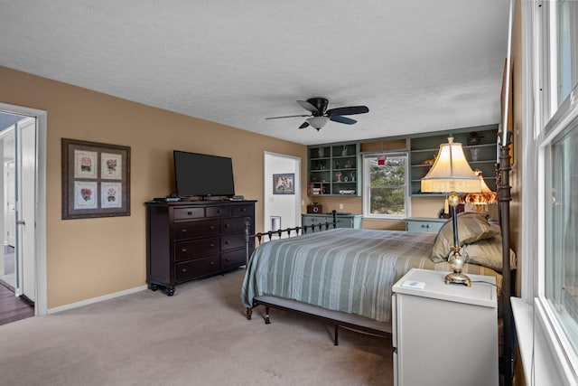 carpeted bedroom featuring ceiling fan and a textured ceiling