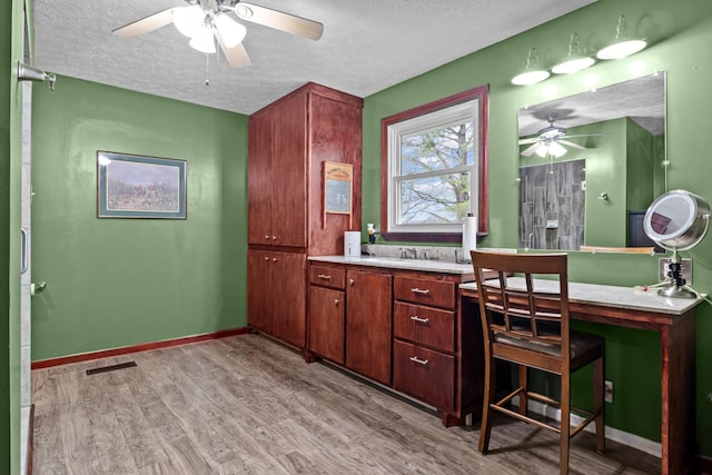 bathroom featuring hardwood / wood-style flooring, vanity, ceiling fan, and a textured ceiling