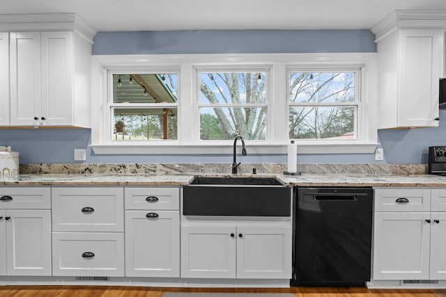 kitchen with a wealth of natural light, black dishwasher, sink, white cabinets, and light stone countertops