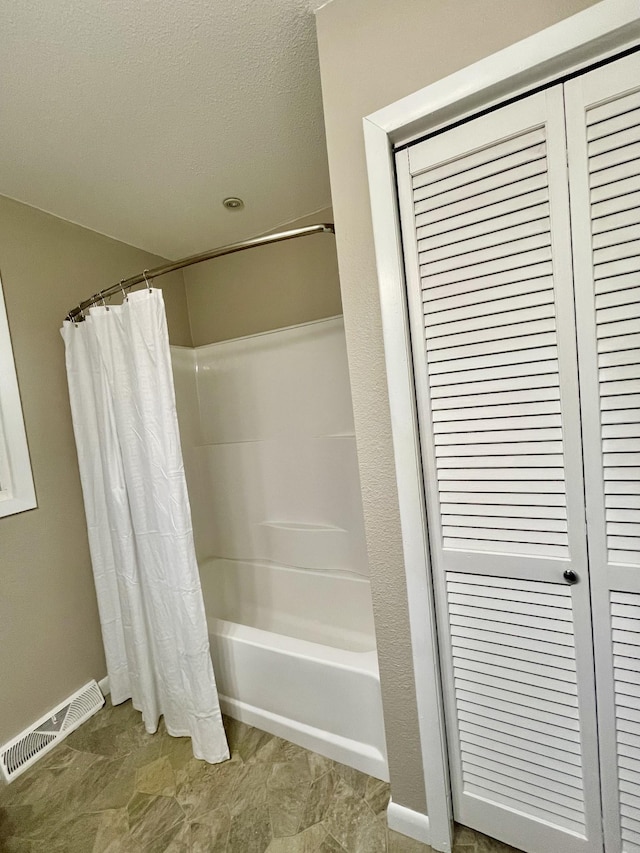 bathroom featuring shower / bath combo with shower curtain and a textured ceiling