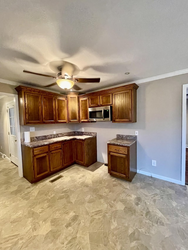 kitchen with crown molding, a textured ceiling, and ceiling fan