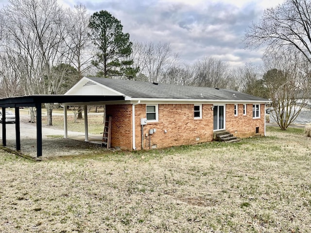 rear view of property with a carport and a yard