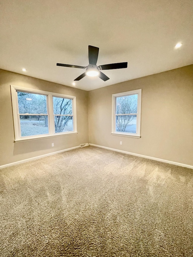 carpeted spare room featuring ceiling fan