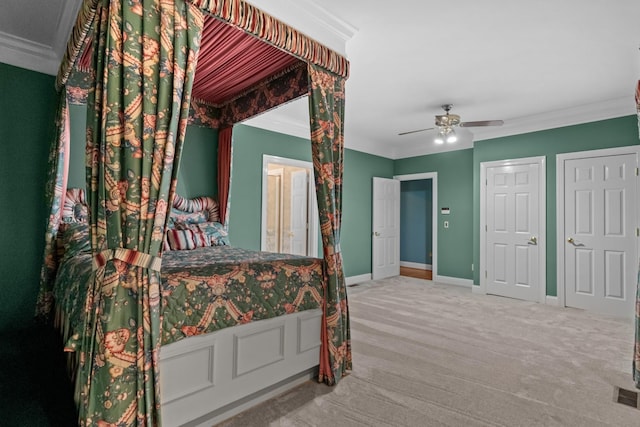 bedroom featuring two closets, ornamental molding, ceiling fan, and carpet flooring