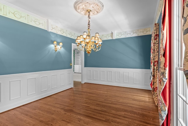 empty room featuring wood-type flooring and a notable chandelier