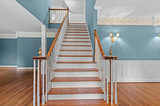 stairway with crown molding and wood-type flooring
