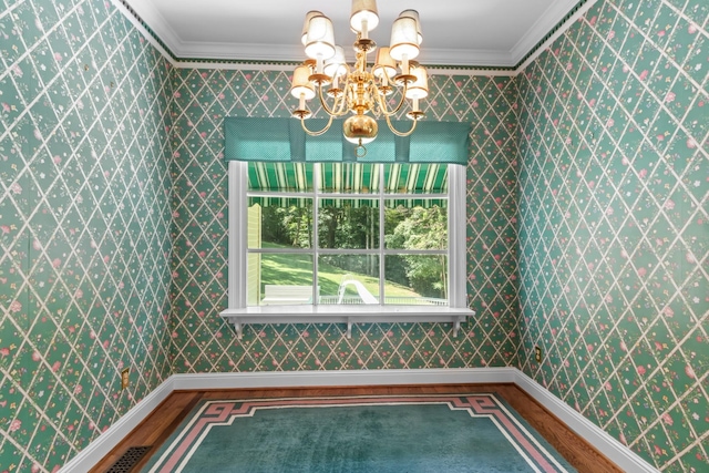 unfurnished dining area with hardwood / wood-style floors, crown molding, and a notable chandelier