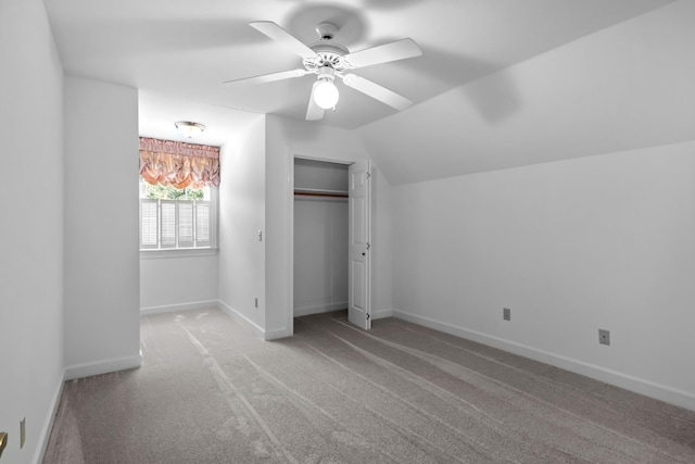 unfurnished bedroom with vaulted ceiling, ceiling fan, carpet floors, and a closet