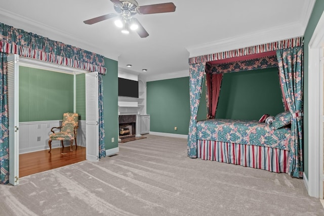 carpeted bedroom with ornamental molding, ceiling fan, and a fireplace