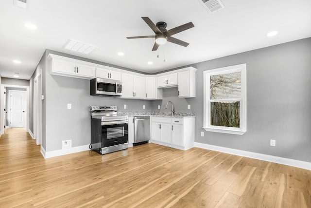 kitchen with sink, light hardwood / wood-style flooring, white cabinets, and appliances with stainless steel finishes