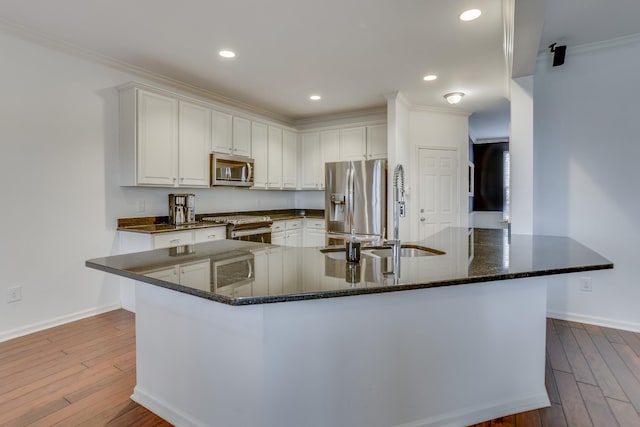 kitchen featuring appliances with stainless steel finishes, sink, white cabinets, and light hardwood / wood-style flooring