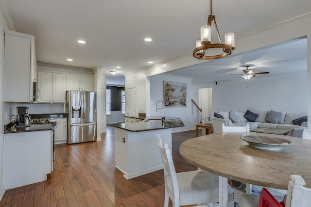 dining area featuring crown molding, sink, ceiling fan with notable chandelier, and dark hardwood / wood-style flooring