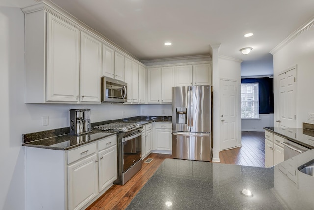 kitchen with appliances with stainless steel finishes, dark hardwood / wood-style floors, and white cabinets