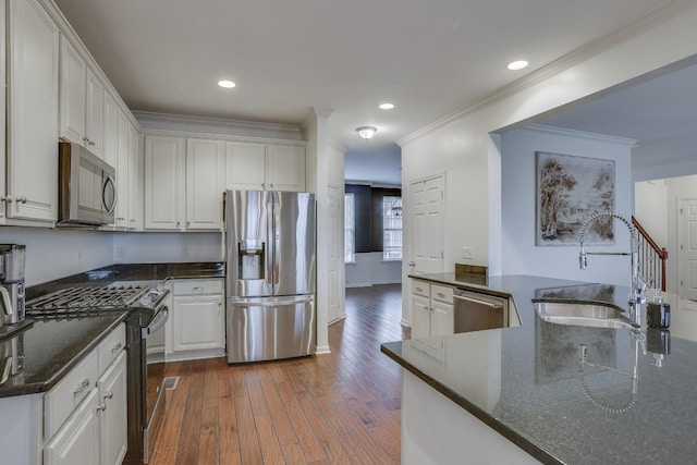 kitchen featuring dark hardwood / wood-style floors, dark stone countertops, white cabinets, kitchen peninsula, and stainless steel appliances