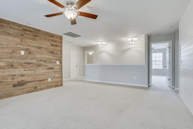 carpeted spare room with ceiling fan and wood walls