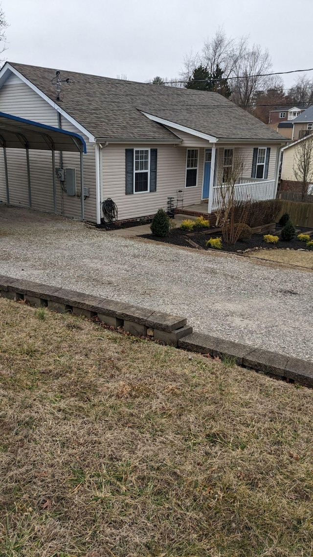 view of front facade with a front yard, a carport, and covered porch