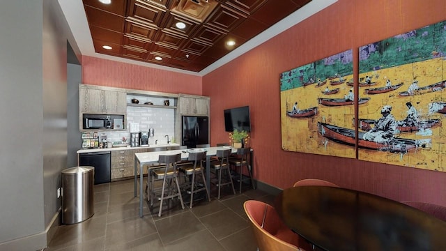 bar with dark tile patterned flooring, backsplash, and black appliances