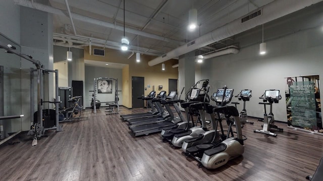 exercise room with a towering ceiling and hardwood / wood-style flooring