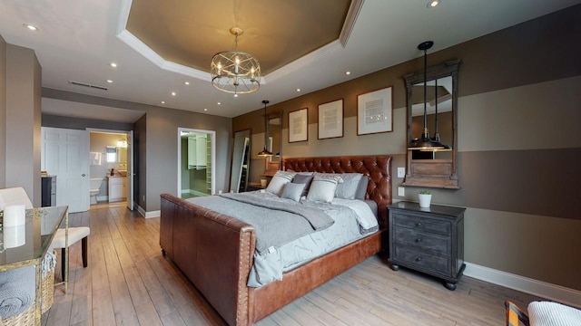 bedroom featuring an inviting chandelier, connected bathroom, a raised ceiling, and light wood-type flooring