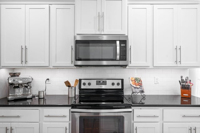 kitchen featuring tasteful backsplash, appliances with stainless steel finishes, dark stone countertops, and white cabinets