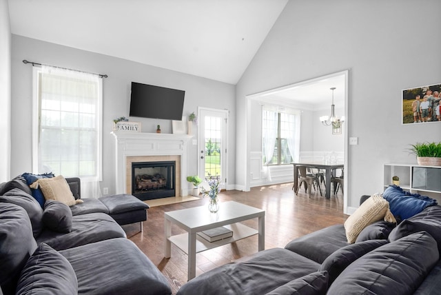 living room with wood-type flooring, high vaulted ceiling, and a chandelier