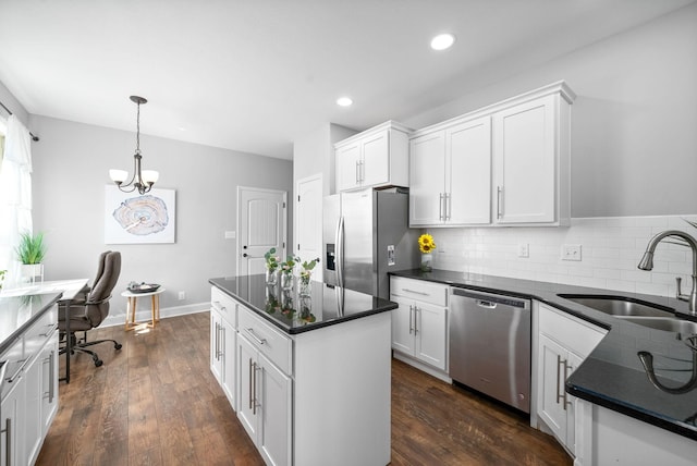 kitchen with appliances with stainless steel finishes, sink, white cabinets, and decorative light fixtures