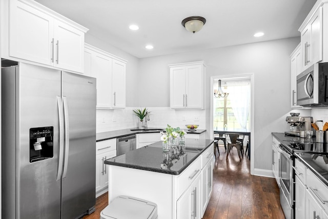 kitchen featuring sink, appliances with stainless steel finishes, backsplash, white cabinets, and a kitchen island