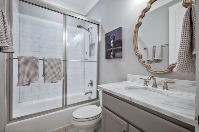 full bathroom featuring vanity, bath / shower combo with glass door, and toilet