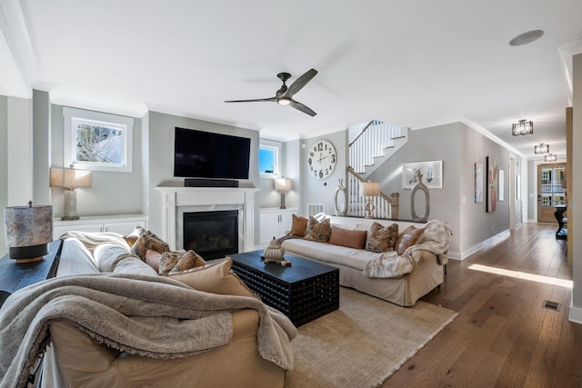 living room featuring crown molding, dark hardwood / wood-style floors, ceiling fan, and a fireplace