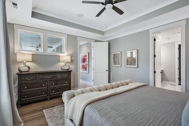 bedroom featuring ceiling fan, crown molding, dark hardwood / wood-style floors, and a raised ceiling