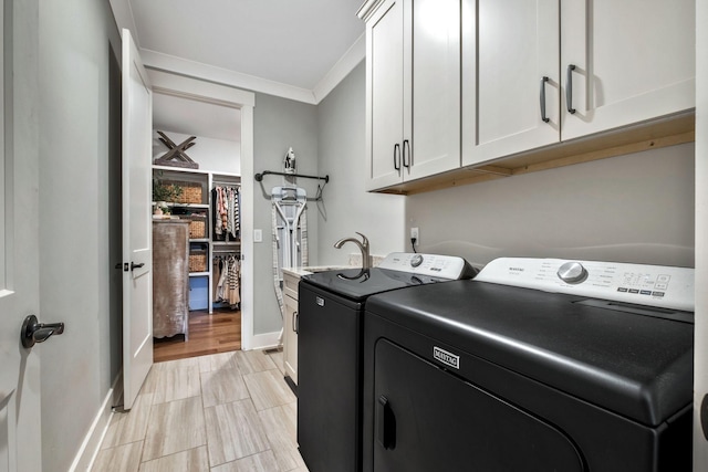 clothes washing area with cabinets, washing machine and dryer, and ornamental molding