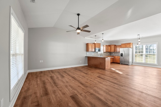 kitchen with decorative light fixtures, light wood-type flooring, ceiling fan, stainless steel appliances, and decorative backsplash