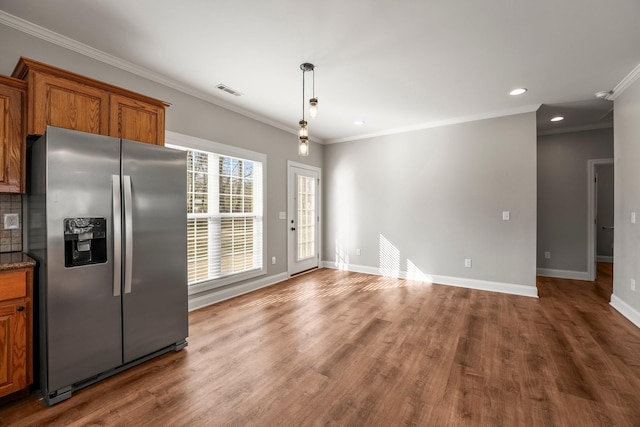 kitchen featuring pendant lighting, hardwood / wood-style flooring, stainless steel fridge, crown molding, and backsplash