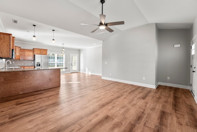 unfurnished living room featuring lofted ceiling, sink, light hardwood / wood-style flooring, and ceiling fan