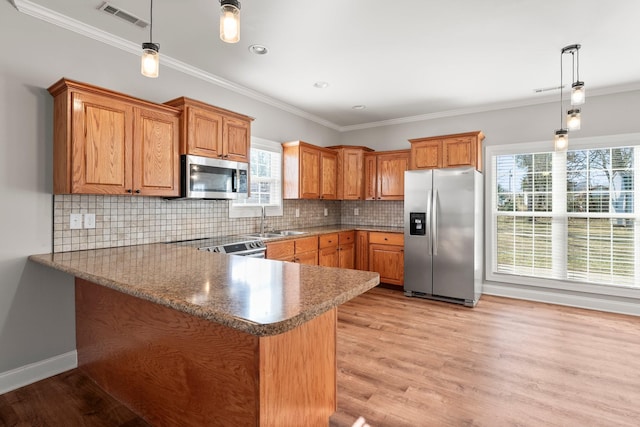 kitchen featuring stainless steel appliances, kitchen peninsula, light wood-type flooring, and decorative light fixtures