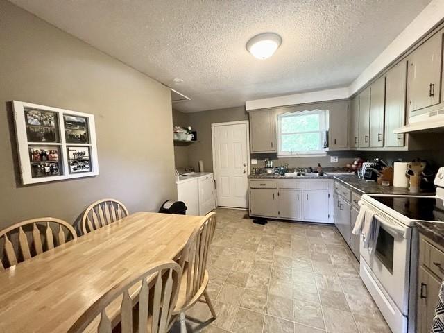 kitchen featuring gray cabinets, washer and dryer, a textured ceiling, and white range with electric cooktop