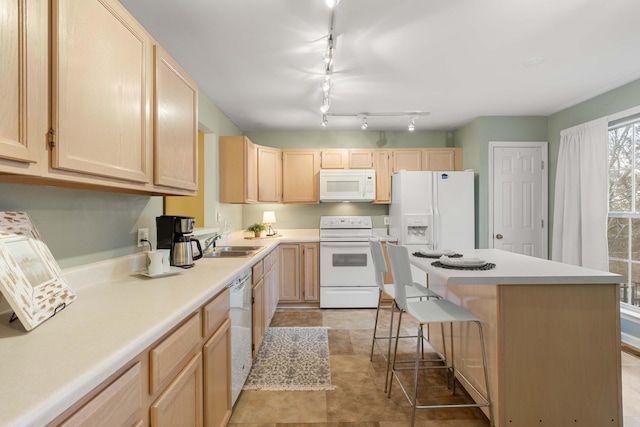 kitchen with sink, white appliances, a kitchen breakfast bar, a kitchen island, and light brown cabinets