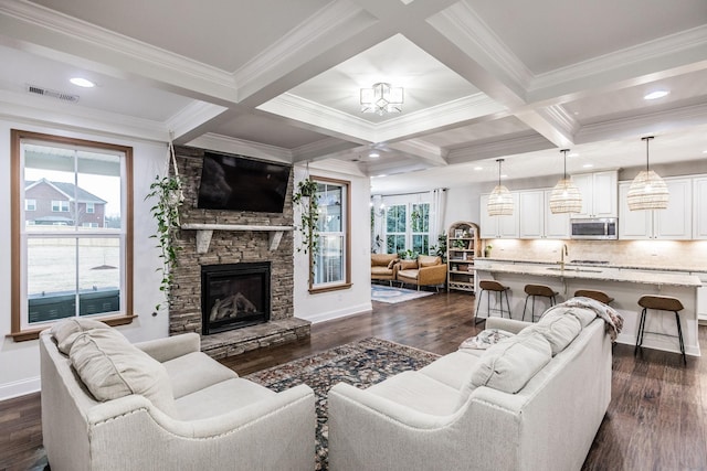 living room featuring dark wood-type flooring, coffered ceiling, beam ceiling, and a stone fireplace