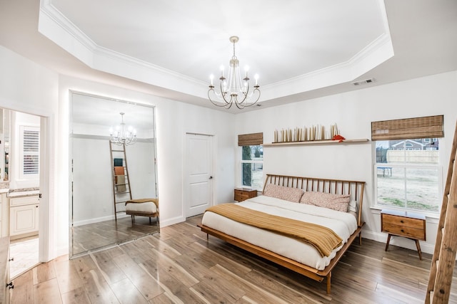 bedroom with an inviting chandelier, a raised ceiling, and hardwood / wood-style floors