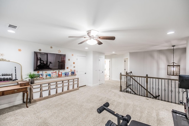 workout area with ceiling fan with notable chandelier and light colored carpet