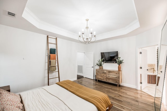 bedroom featuring crown molding, a tray ceiling, wood-type flooring, and a chandelier