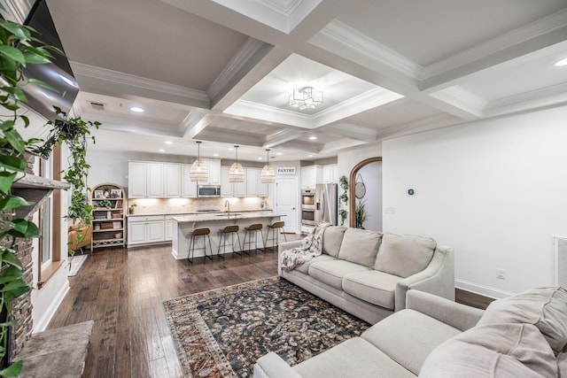 living room with dark wood-type flooring, coffered ceiling, sink, crown molding, and beam ceiling