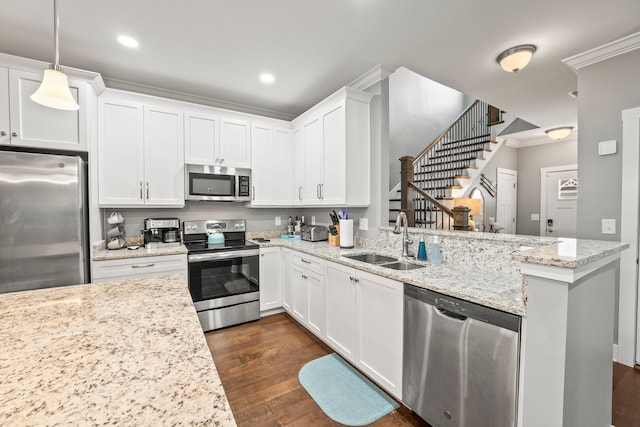 kitchen featuring stainless steel appliances, sink, white cabinets, and decorative light fixtures