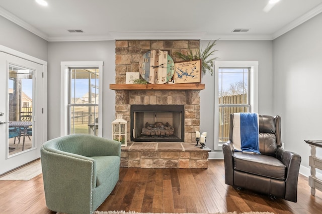 living area with crown molding, wood-type flooring, and a fireplace