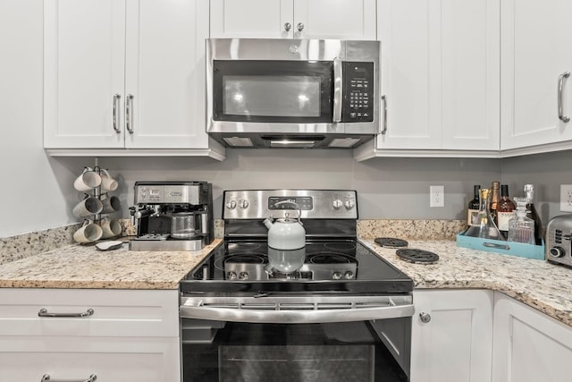 kitchen featuring light stone countertops, stainless steel appliances, and white cabinets